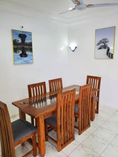 un tavolo da pranzo con sedie e un tavolo e sedie in legno di Agimlog a Allada