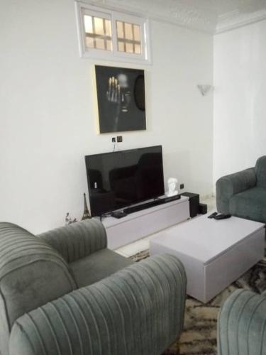 uma sala de estar com 2 sofás e uma televisão de ecrã plano em Agimlog em Allada