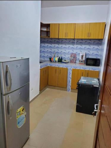 La cuisine est équipée d'un réfrigérateur en acier inoxydable et de placards en bois. dans l'établissement Agimlog, à Allada