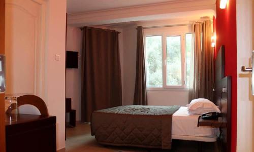 een hotelkamer met een bed en een raam bij HOTEL DU NORD in Bejaïa