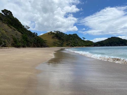 a sandy beach with a hill in the background at Tutukaka Sunrise in Tutukaka