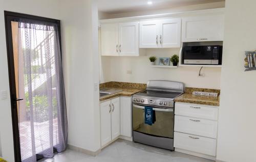 a kitchen with white cabinets and a stove top oven at The Beach House Ground Floor Condo in Coco