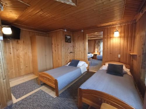 Bańska NiżnaにあるBrzoskwiniowy Domの木製の壁の部屋にベッドが2つある