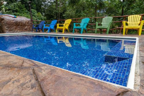 a swimming pool with colorful chairs and chairs around it at Hidden Paradise Lodge in Drake