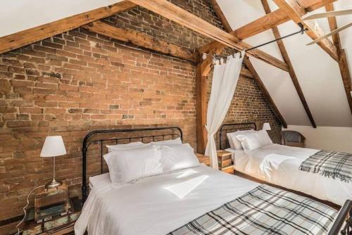 two beds in a room with a brick wall at MTL Artist Loft - Champs in Montréal