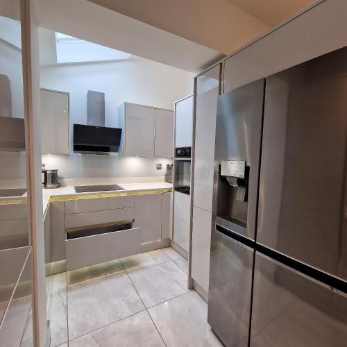 a kitchen with a stainless steel refrigerator at Delightful & Spacious Guest House in Farnworth Near Bolton Hospital in Farnworth