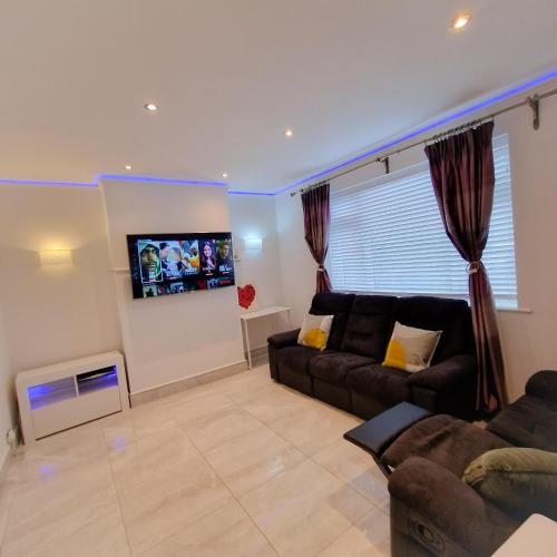 a living room with a couch and a flat screen tv at Delightfully & Spacious Guest House in Farnworth in Farnworth