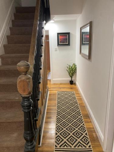 a hallway with stairs and a rug on the floor at The elegant Garden Room in Blackpool