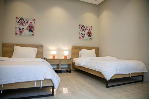 a bedroom with two beds and two lamps on a table at المرفأ 2 شاليه مع مسبح والعاب مائية وغرف نوم فاخرة in Khalij Salman