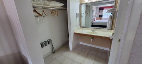 a bathroom with a sink and a mirror and a bed at Ramada by Wyndham Mountain Home in Mountain Home