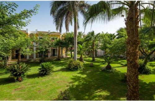 a yard with palm trees and a building at Lillyland Mirage Bay & Aqua Park in Hurghada