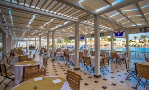 a restaurant with tables and chairs and a pool at Lillyland Mirage Bay & Aqua Park in Hurghada