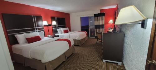 a hotel room with two beds with red walls at Ramada by Wyndham Mountain Home in Mountain Home