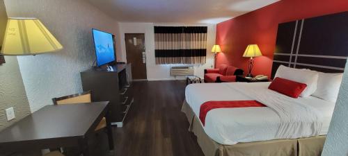 a hotel room with a large bed and a red wall at Ramada by Wyndham Mountain Home in Mountain Home