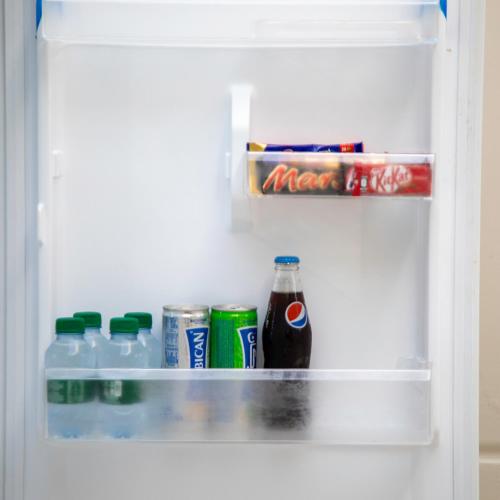 a refrigerator filled with drinks and soda at شاليه المرفأ بمسبح اطفال والعاب مائية وغرفتين نوم فاخرة in Khalij Salman