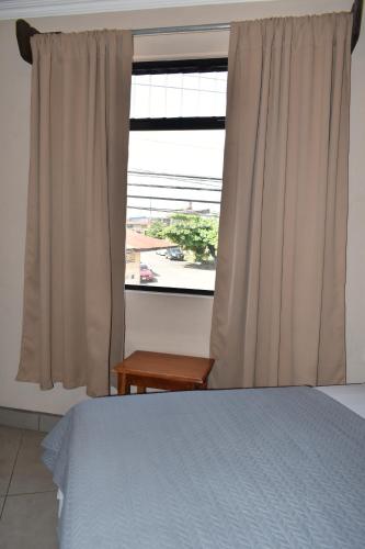 a bedroom with a bed and a large window at Hotel Cabinas Midey in Puntarenas