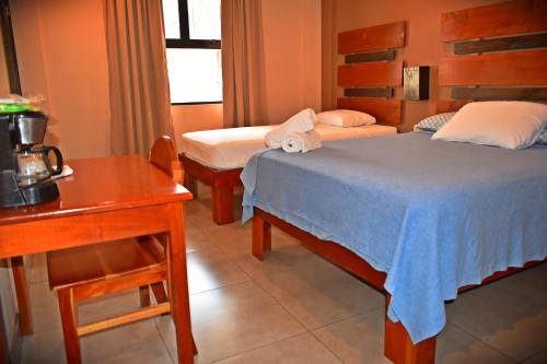 um quarto de hotel com duas camas e uma mesa e uma secretária em Hotel Cabinas Midey em Puntarenas