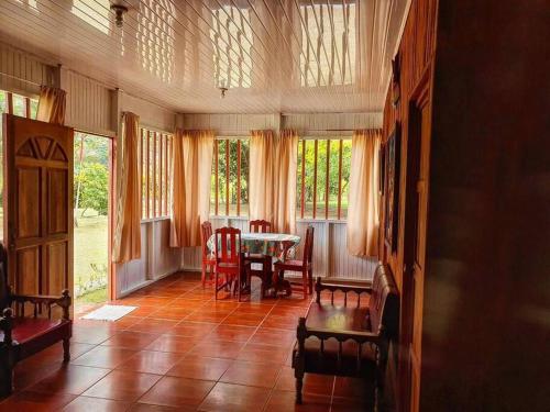 a living room with a table and chairs and windows at Villa Montezuma Corcovado in Puerto Jiménez