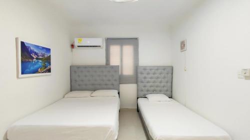 2 camas en una habitación con paredes blancas en apartamento Ana ciudad amurallada en Cartagena de Indias