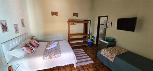 Schlafzimmer mit einem weißen Bett und einem TV in der Unterkunft Hippocampo Ilhabela in Ilhabela
