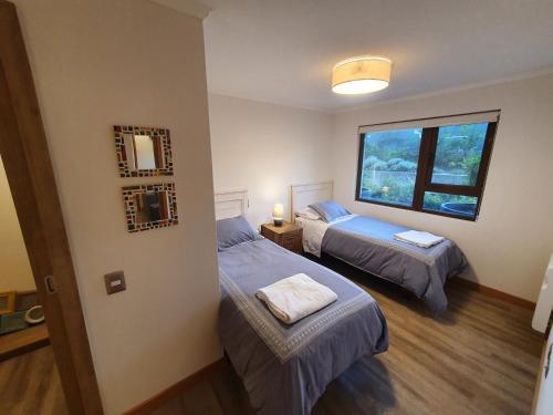 a bedroom with two beds and a window at Acogedor Departamento a pasos del Lago Llanquihue in Puerto Varas