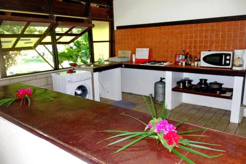 a kitchen with a table with flowers on it at Pension Les Trois Cascades in Uturoa
