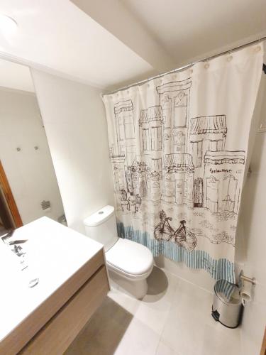 a bathroom with a toilet and a shower curtain at Acogedor Departamento a pasos del Lago Llanquihue in Puerto Varas