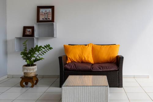 a brown couch with an orange pillow in a living room at Wayana - DestinationGuyane - séjours en famille personnalisé in Cabassou