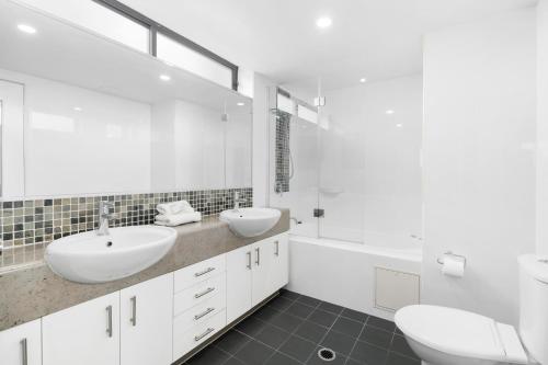 a white bathroom with two sinks and a tub at Aqualine Apartments On The Broadwater in Gold Coast