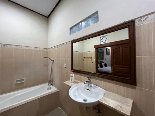 a bathroom with a sink and a mirror and a tub at Nari Homestay in Canggu