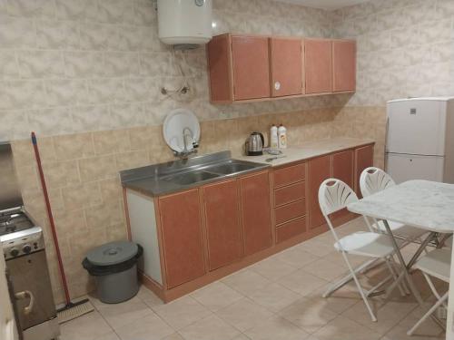 a kitchen with a sink and a table with chairs at شقق نجوم الجزيرة للشقق المخدومة in Tabuk