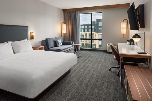 セントポールにあるCourtyard by Marriott St Paul Downtownのベッドとデスクが備わるホテルルームです。