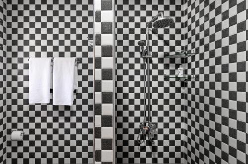 uma casa de banho com um chuveiro com azulejos pretos e brancos em Creole Breeze Self Catering Apartments em Mahé