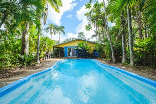 a swimming pool in front of a house with palm trees at Getaways at Byfield in Byfield