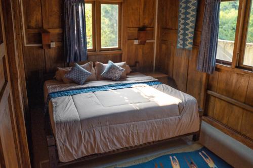 a bed in a room with wooden walls and windows at Secret Joglo Lebih in Lebih
