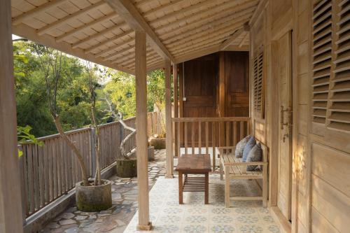 a porch of a house with a wooden pergola at Secret Joglo Lebih in Lebih