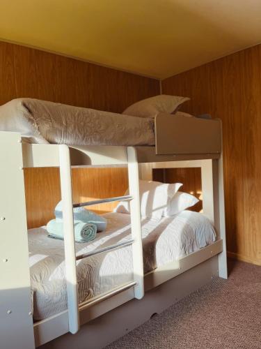 two bunk beds in a room with white sheets and pillows at Mehuín el Remanso de Paz in Mehuín