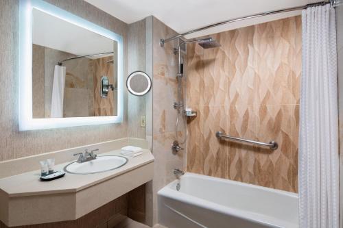 een badkamer met een wastafel, een bad en een spiegel bij The Westin Southfield Detroit in Southfield