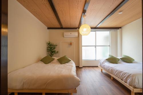two beds in a room with a window at 【鶴木宿】 in Osaka