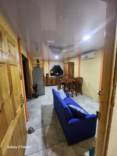 uma sala de estar com um sofá azul e uma cozinha em Inf casa vacacional 