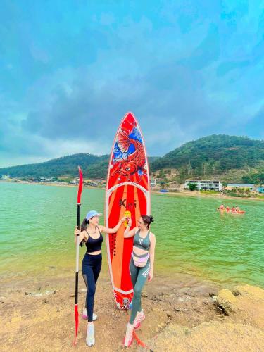 two women standing on the beach with a surfboard at Lagom Village (Glamping Site) in Hanoi