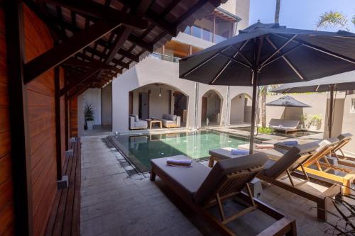 a pool with chairs and an umbrella next to a building at BK Beach Boutique Hotel - Hikkaduwa in Hikkaduwa
