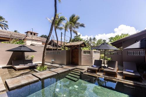a pool with chairs and umbrellas next to a house at BK Beach Boutique Hotel - Hikkaduwa in Hikkaduwa