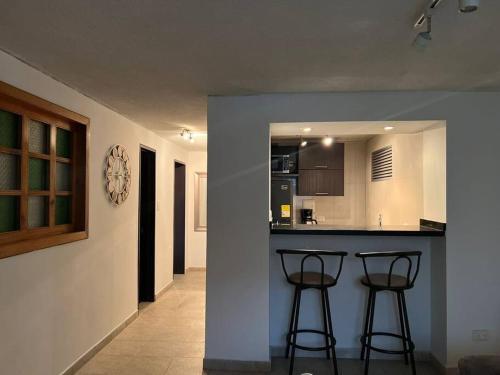 een keuken met twee barkrukken aan een balie bij LA CASA DEL CABLE -Atractivo Único Sector Cable 104- in Manizales
