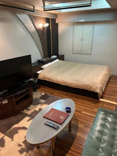 a room with a bed and a table and a tv at Hotel AKAIKUTSU - Adult Only in Yokohama