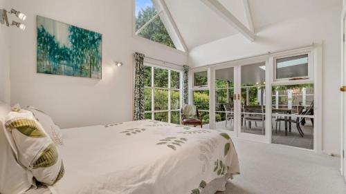 a white bedroom with a bed and a dining room at Jamieson Cottage in Wentworth Falls