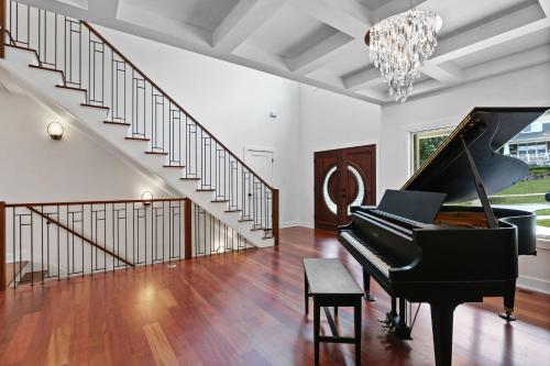 a living room with a piano and a staircase at Luxurious Mansion, Deck, Patio, Chef’s Kitchen in Crown Point