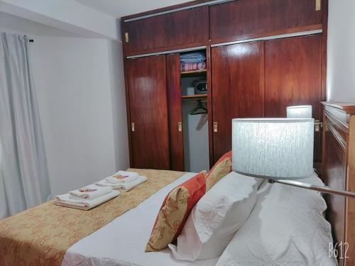 a small bedroom with a bed with a lamp at Los Tres Lapachos "Orange" in Salta