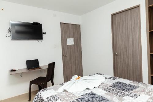 Schlafzimmer mit einem Bett, einem Schreibtisch und einem TV in der Unterkunft Hotel Galanni in Valledupar