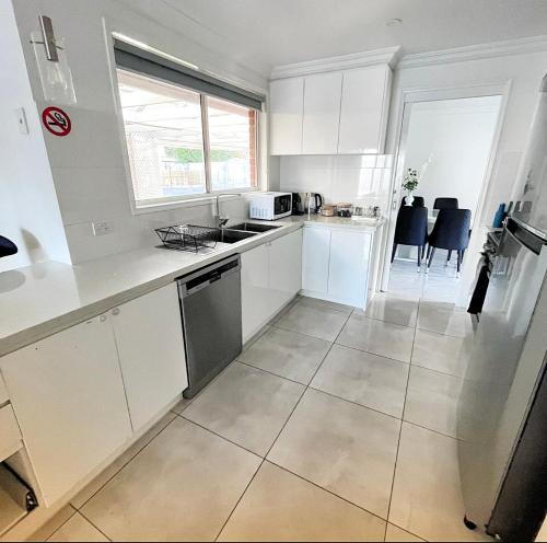 a kitchen with white cabinets and a large tile floor at Luxurious Family Home in Sydenham